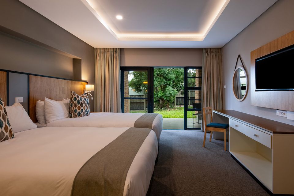 A twin room at Skukuza Safari Lodge with doors onto a patio.